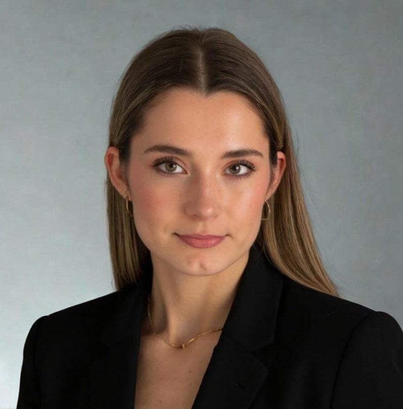 a woman wearing a black suit and gold necklace